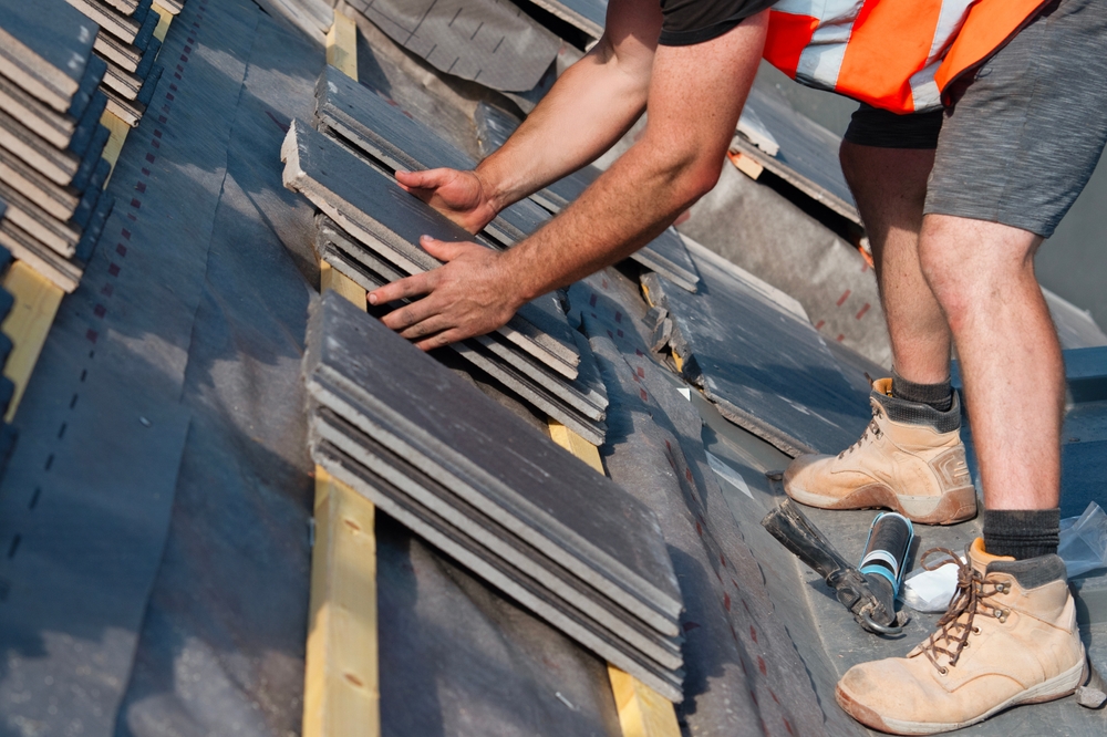 Roofing worker installing a residential roof with safety gear
